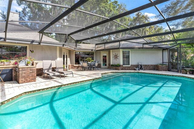 view of pool with glass enclosure and a patio