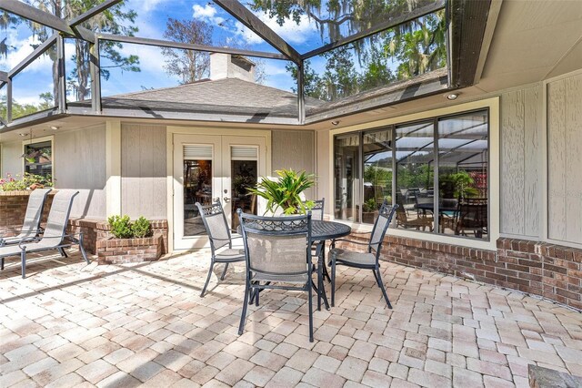 view of patio featuring glass enclosure and french doors