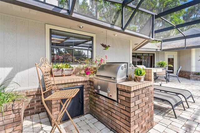 view of patio featuring grilling area, an outdoor kitchen, and a lanai