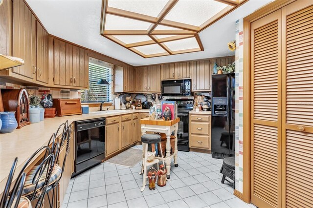 kitchen featuring black appliances, light tile patterned floors, and sink