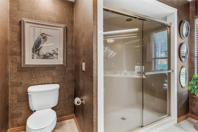 bathroom featuring tile patterned flooring, toilet, and walk in shower