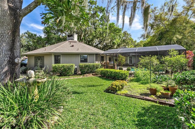 back of house with a lawn and a lanai