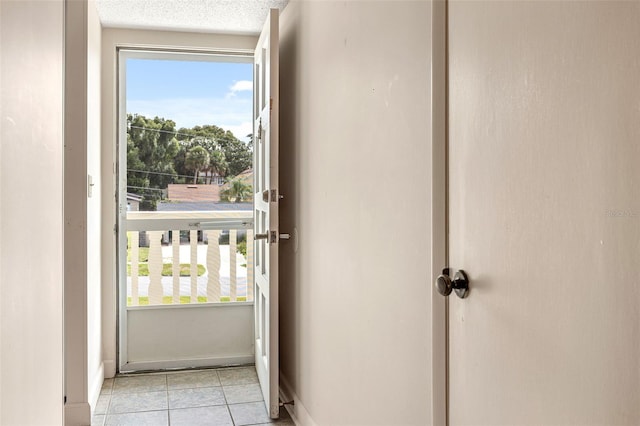 doorway to outside with a textured ceiling and light tile patterned flooring