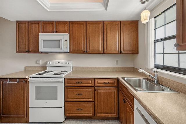 kitchen with crown molding, white appliances, decorative light fixtures, sink, and a raised ceiling