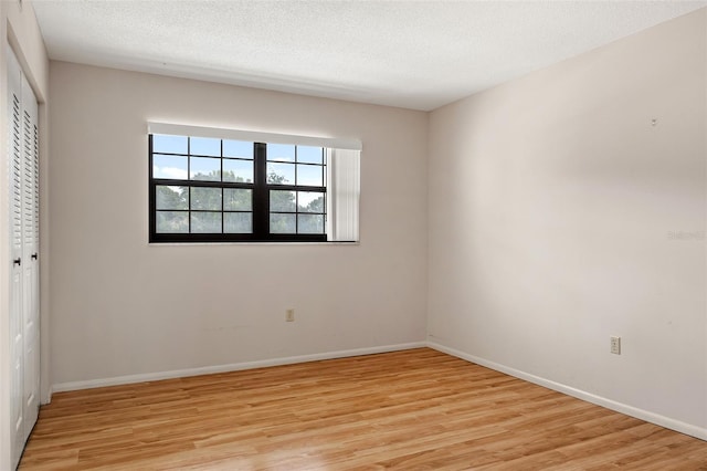 unfurnished bedroom featuring a textured ceiling, light hardwood / wood-style flooring, and a closet