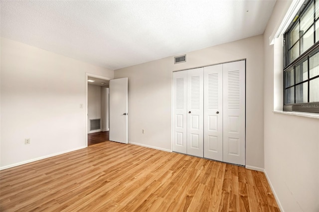 unfurnished bedroom featuring a closet, light hardwood / wood-style floors, and a textured ceiling