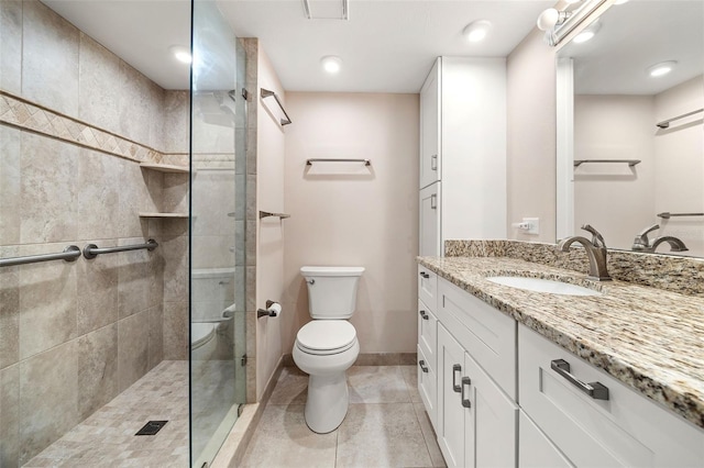 bathroom with tile patterned floors, tiled shower, toilet, and vanity