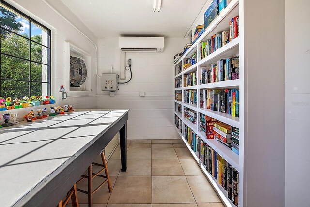 interior space featuring tile countertops, light tile patterned floors, wood walls, and an AC wall unit