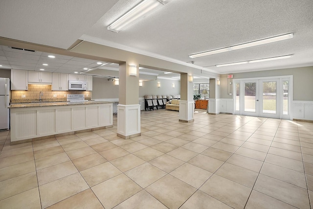 interior space featuring ornamental molding, light tile patterned floors, sink, french doors, and ornate columns