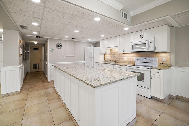 kitchen featuring light stone countertops, white appliances, a center island, sink, and white cabinetry