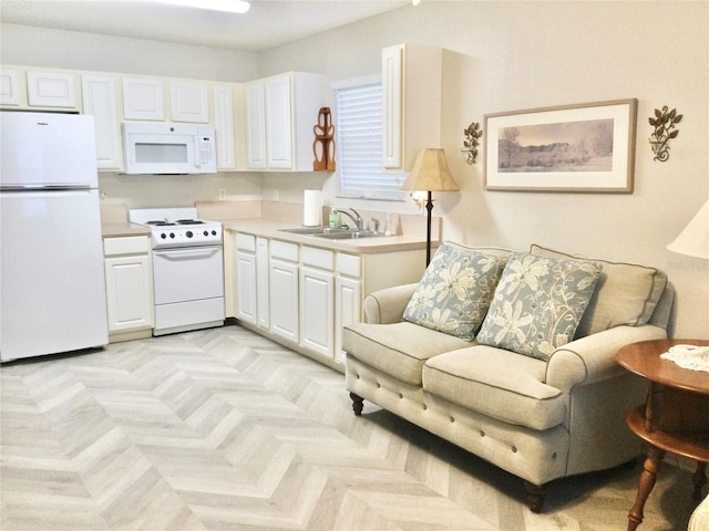 kitchen with sink, white appliances, white cabinets, and light parquet flooring