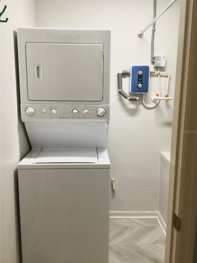 washroom featuring parquet floors and stacked washer / dryer