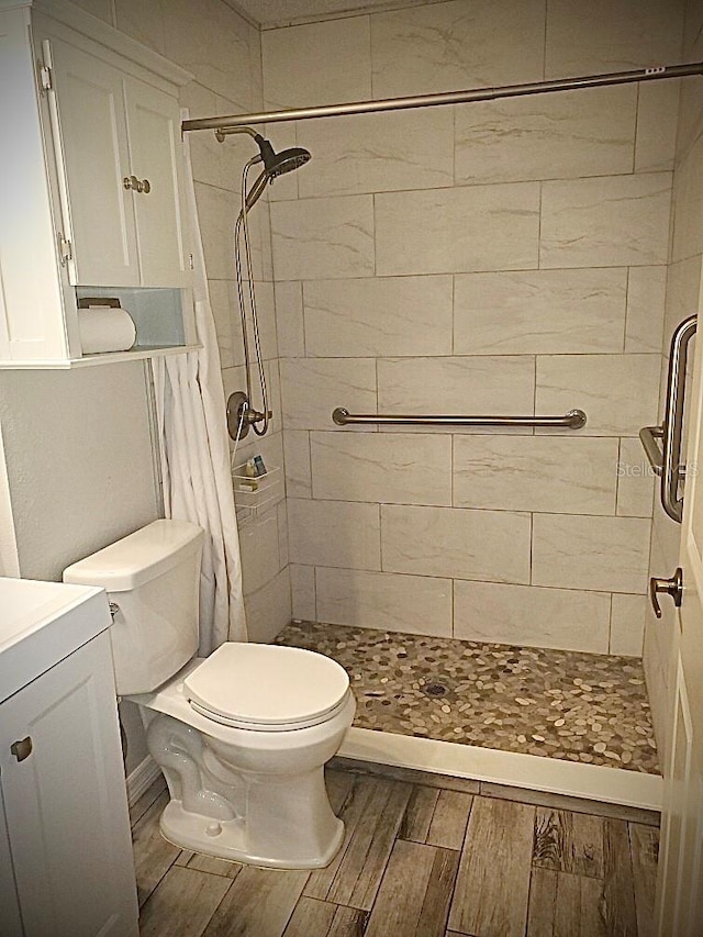 bathroom with toilet, a shower with curtain, hardwood / wood-style flooring, and vanity