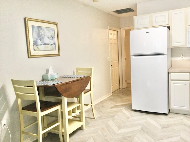 kitchen with white appliances, white cabinetry, and light parquet flooring