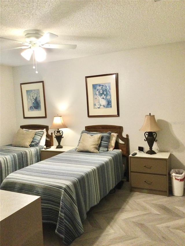 bedroom with ceiling fan, light colored carpet, and a textured ceiling