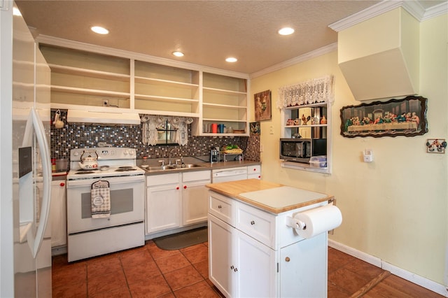 kitchen with dark tile patterned flooring, white appliances, white cabinetry, sink, and tasteful backsplash