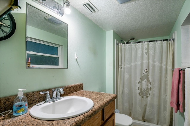 bathroom featuring a textured ceiling, vanity, toilet, and curtained shower