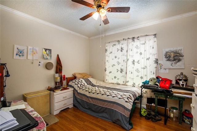 bedroom featuring a textured ceiling, dark wood-type flooring, ceiling fan, and ornamental molding