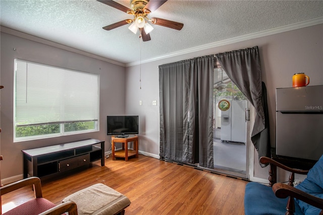 living room featuring light wood-type flooring, ceiling fan, a textured ceiling, and ornamental molding