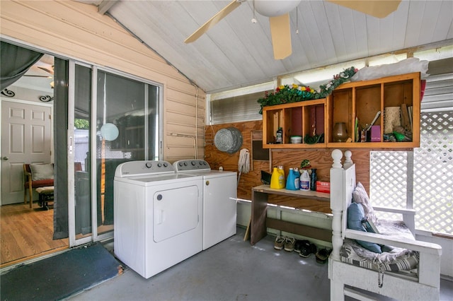 washroom with wood walls, plenty of natural light, washer and clothes dryer, and ceiling fan