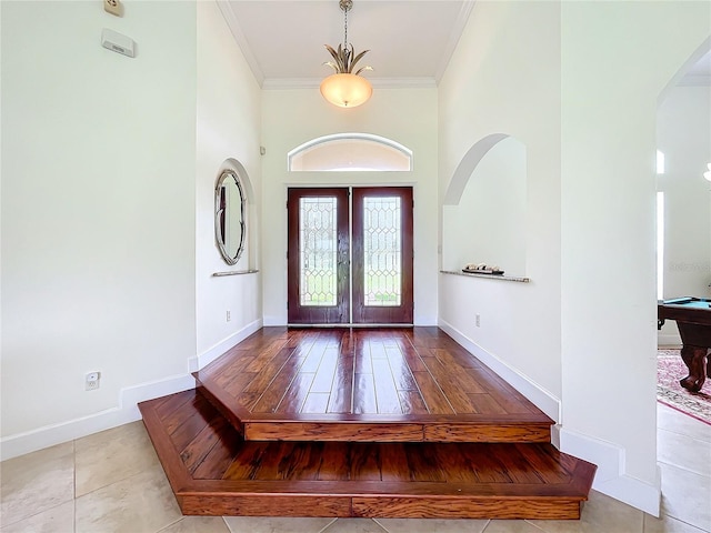 foyer featuring pool table, light hardwood / wood-style flooring, crown molding, a high ceiling, and french doors