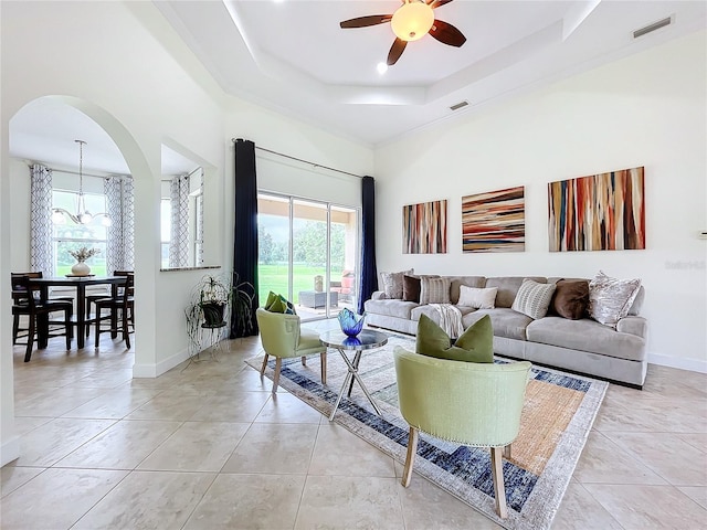 living room featuring light tile patterned flooring, a tray ceiling, and ceiling fan