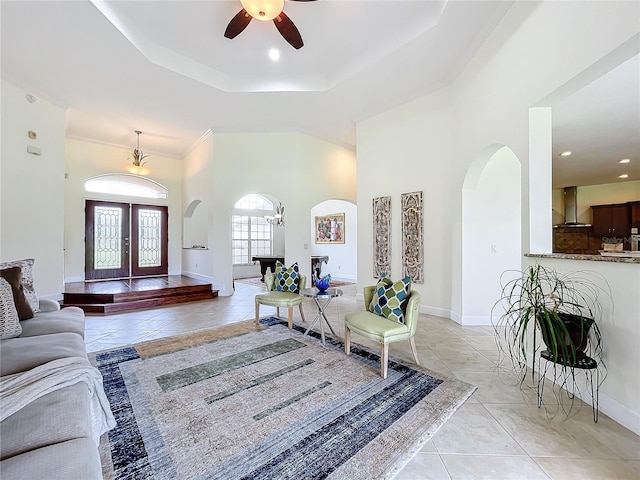 tiled living room with crown molding, ceiling fan, and a raised ceiling