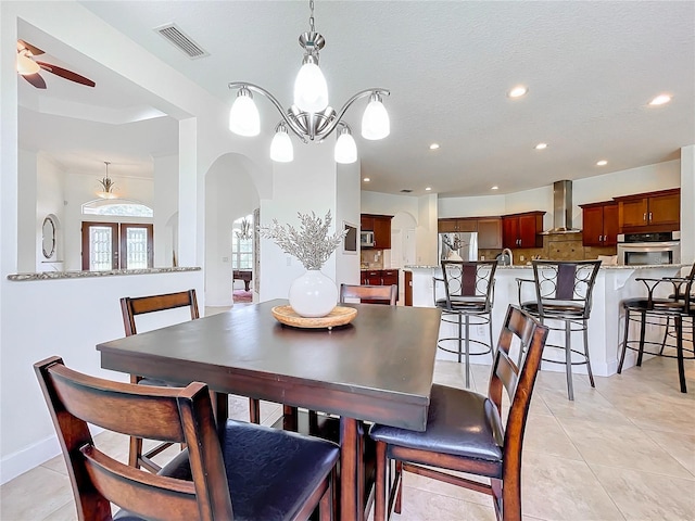 dining space with ceiling fan with notable chandelier, a textured ceiling, and light tile patterned flooring