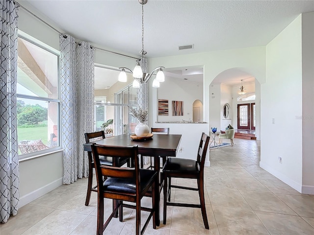 dining room with a notable chandelier, a textured ceiling, and light tile patterned flooring