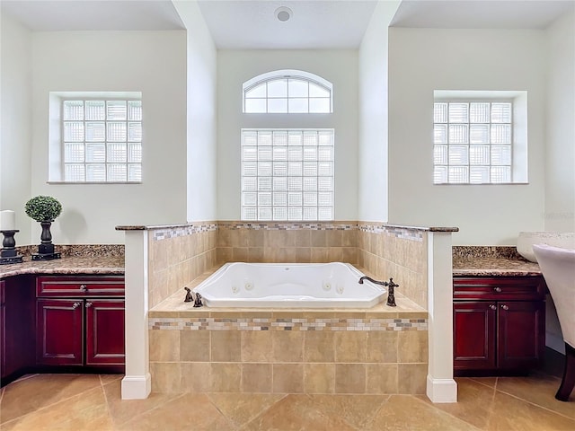 bathroom with tiled tub, vanity, and tile patterned flooring