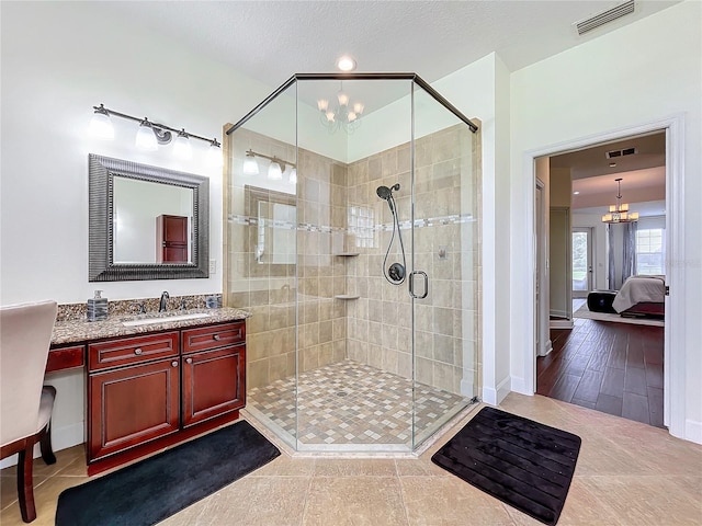 bathroom featuring a textured ceiling, an inviting chandelier, walk in shower, hardwood / wood-style floors, and vanity