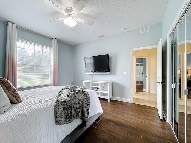 bedroom featuring a closet, ceiling fan, a textured ceiling, and dark hardwood / wood-style flooring