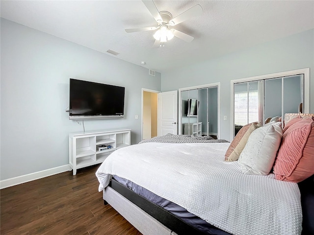 bedroom featuring ceiling fan, multiple closets, and dark hardwood / wood-style flooring