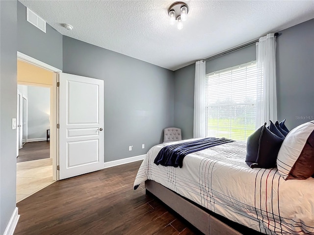 bedroom with a textured ceiling and dark wood-type flooring