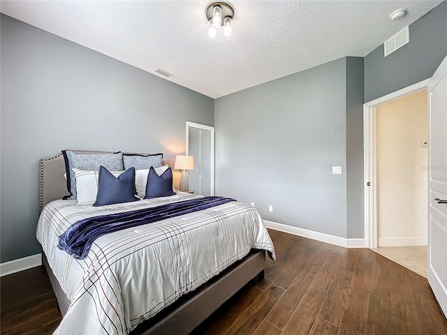 bedroom with a textured ceiling and dark hardwood / wood-style flooring