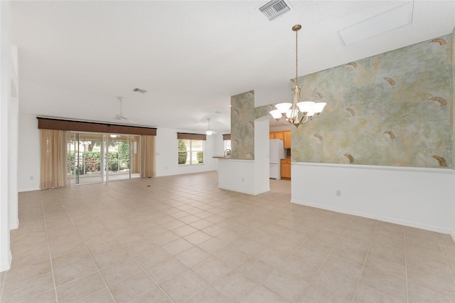 empty room with ceiling fan with notable chandelier and light tile patterned floors