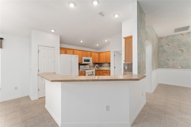 kitchen with kitchen peninsula, light tile patterned floors, a textured ceiling, vaulted ceiling, and white appliances