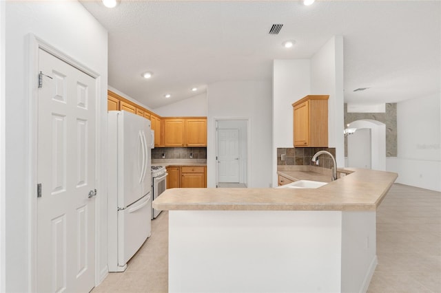 kitchen featuring kitchen peninsula, lofted ceiling, light brown cabinetry, light tile patterned flooring, and white appliances