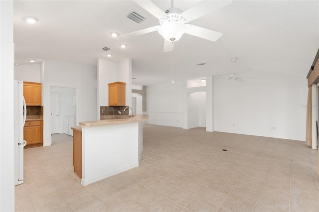 kitchen with backsplash, lofted ceiling, kitchen peninsula, and white refrigerator