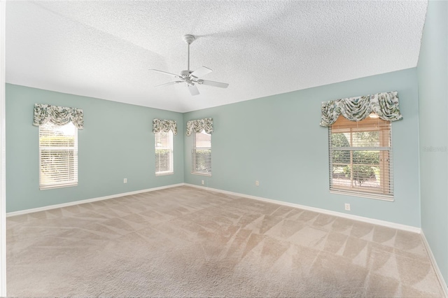 carpeted empty room with a textured ceiling, a healthy amount of sunlight, and ceiling fan