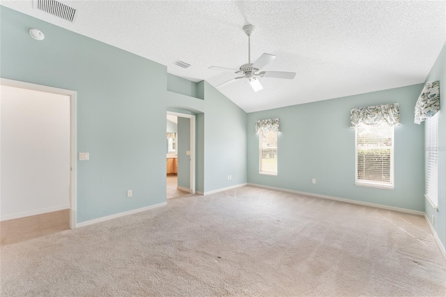 spare room featuring light carpet, lofted ceiling, and ceiling fan