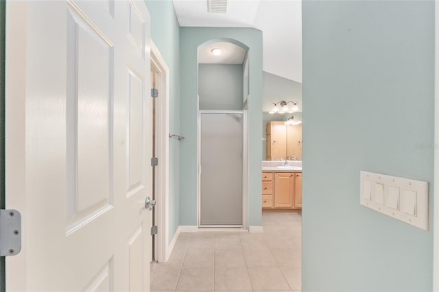 hall featuring sink, lofted ceiling, and light tile patterned flooring