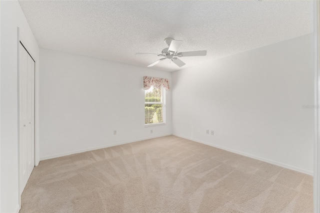 unfurnished bedroom featuring a closet, a textured ceiling, light colored carpet, and ceiling fan