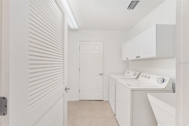 clothes washing area with sink, light tile patterned flooring, cabinets, a textured ceiling, and washing machine and dryer