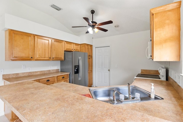 kitchen featuring ceiling fan, stove, sink, stainless steel fridge with ice dispenser, and vaulted ceiling