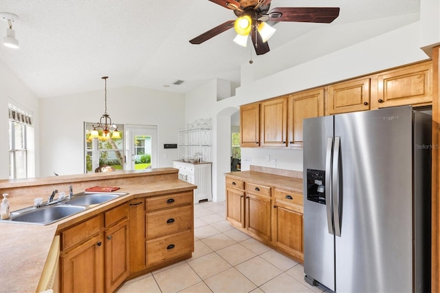 kitchen featuring vaulted ceiling, ceiling fan with notable chandelier, pendant lighting, stainless steel refrigerator with ice dispenser, and sink