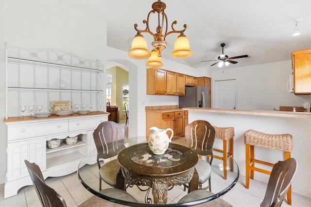 dining space with ceiling fan with notable chandelier and light tile patterned floors