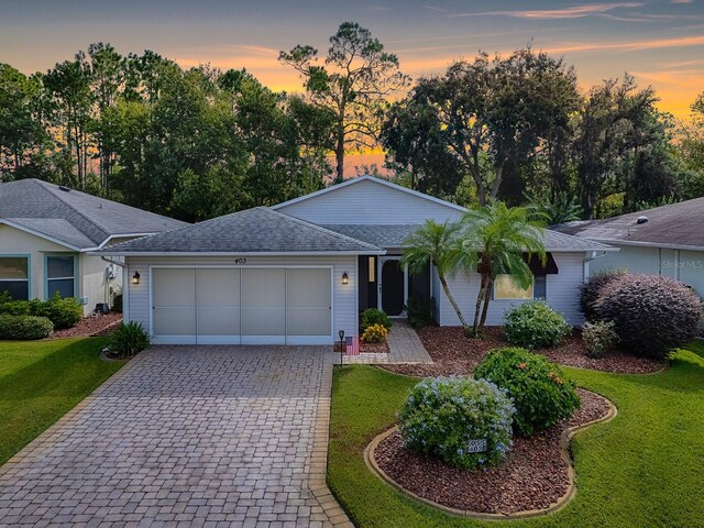 ranch-style home featuring a garage and a lawn