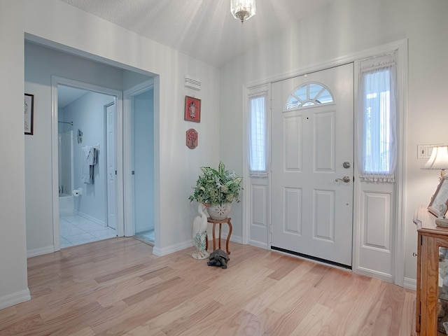 entrance foyer with light hardwood / wood-style floors and a textured ceiling