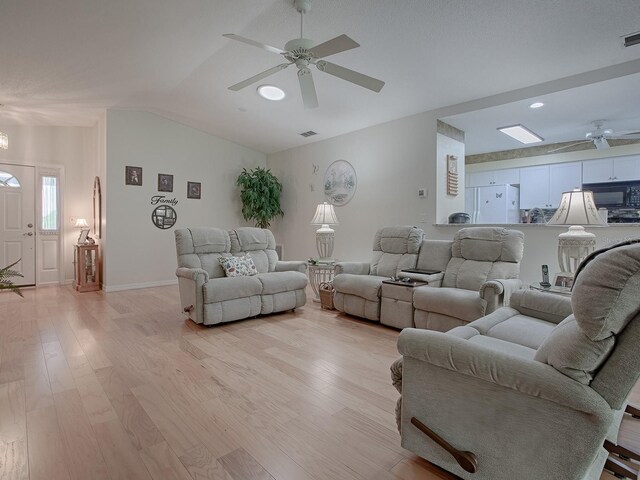 living room featuring lofted ceiling, light hardwood / wood-style flooring, and ceiling fan